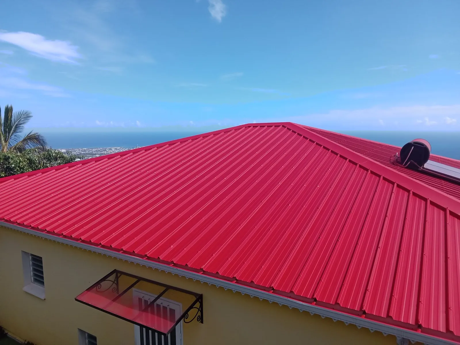 Toiture en tôle rouge rénovée par HART TOITURE face à l’océan